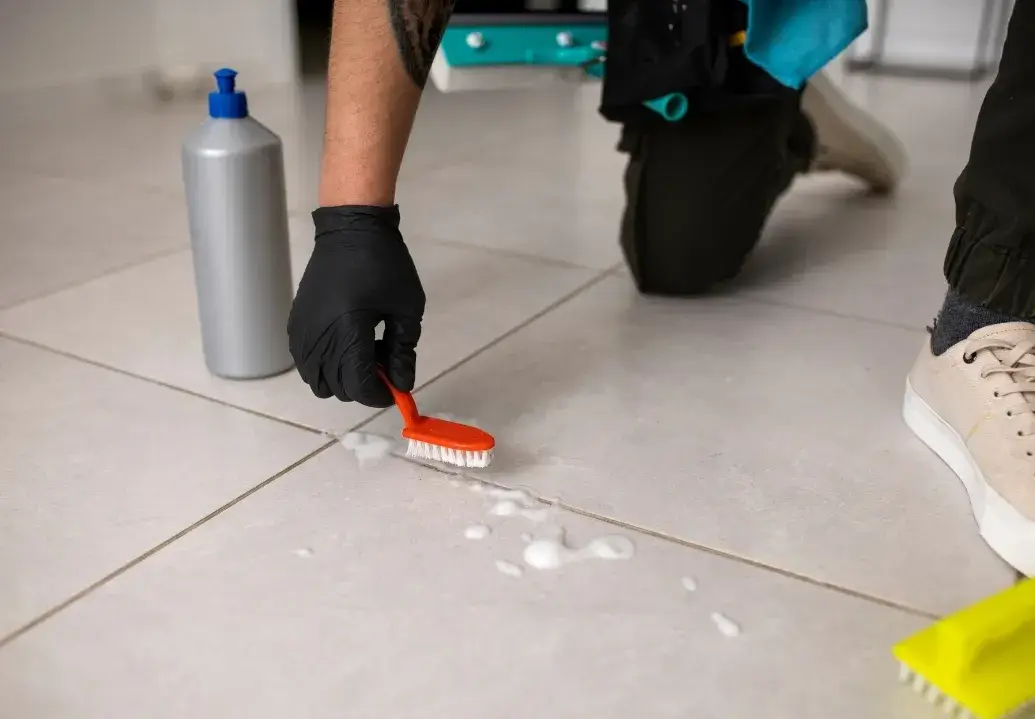 Technician scrubbing floor tiles and grout after renovation using deep cleaning products